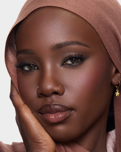 Woman wearing a brown hijab against a plain background